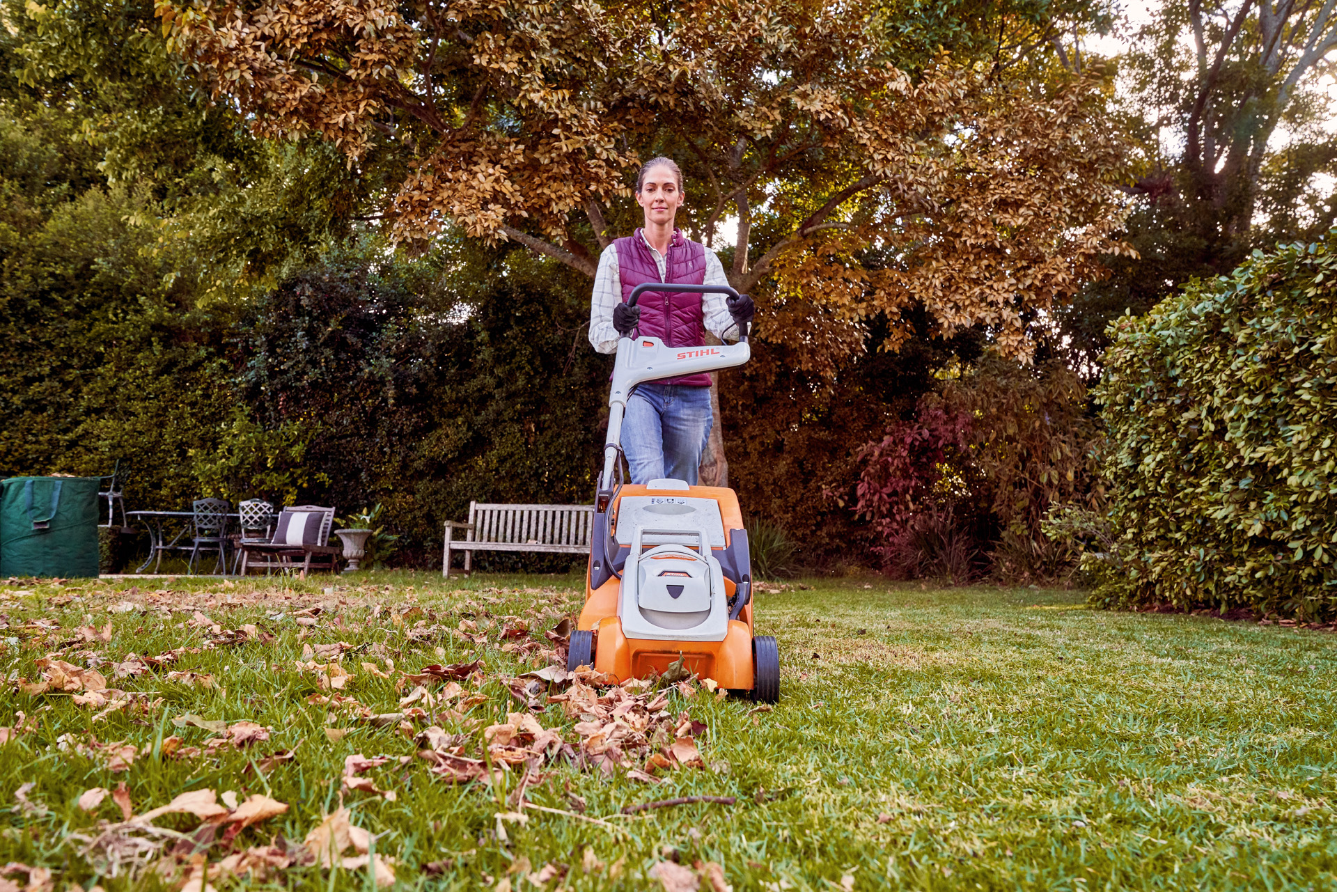 Žena koristi STIHL baterijsku kosačicu RMA 339 C za održavanje travnjaka u bašti u jesen
