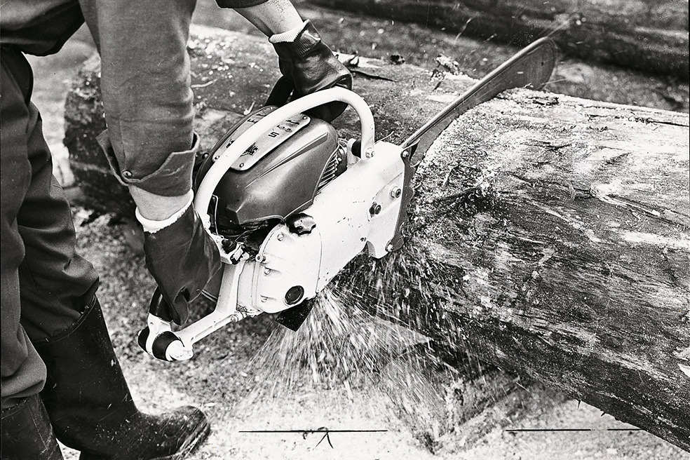 Stara crno-bela fotografija osobe koja preseca drvo motornom testerom STIHL Contra 
