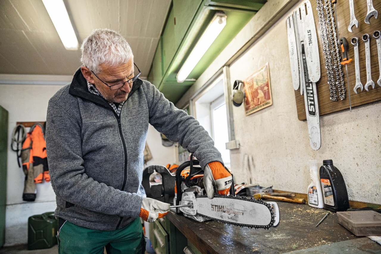 Čovek u radionici radi na motornoj testeri sa vodilicom STIHL Rollomatic E 