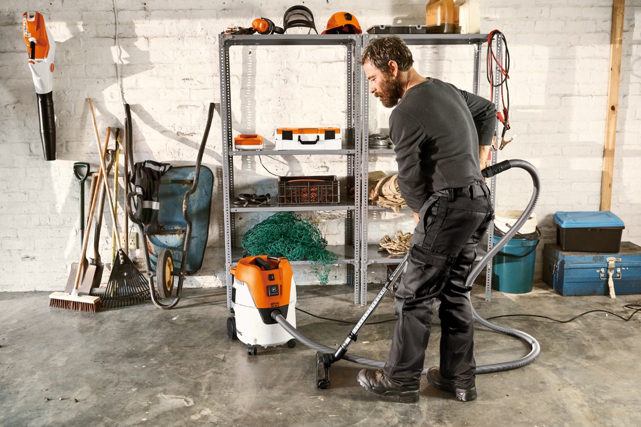 Muškarac usisava pod u garaži usisivačem za mokro/suvo usisavanje STIHL SE 62 E