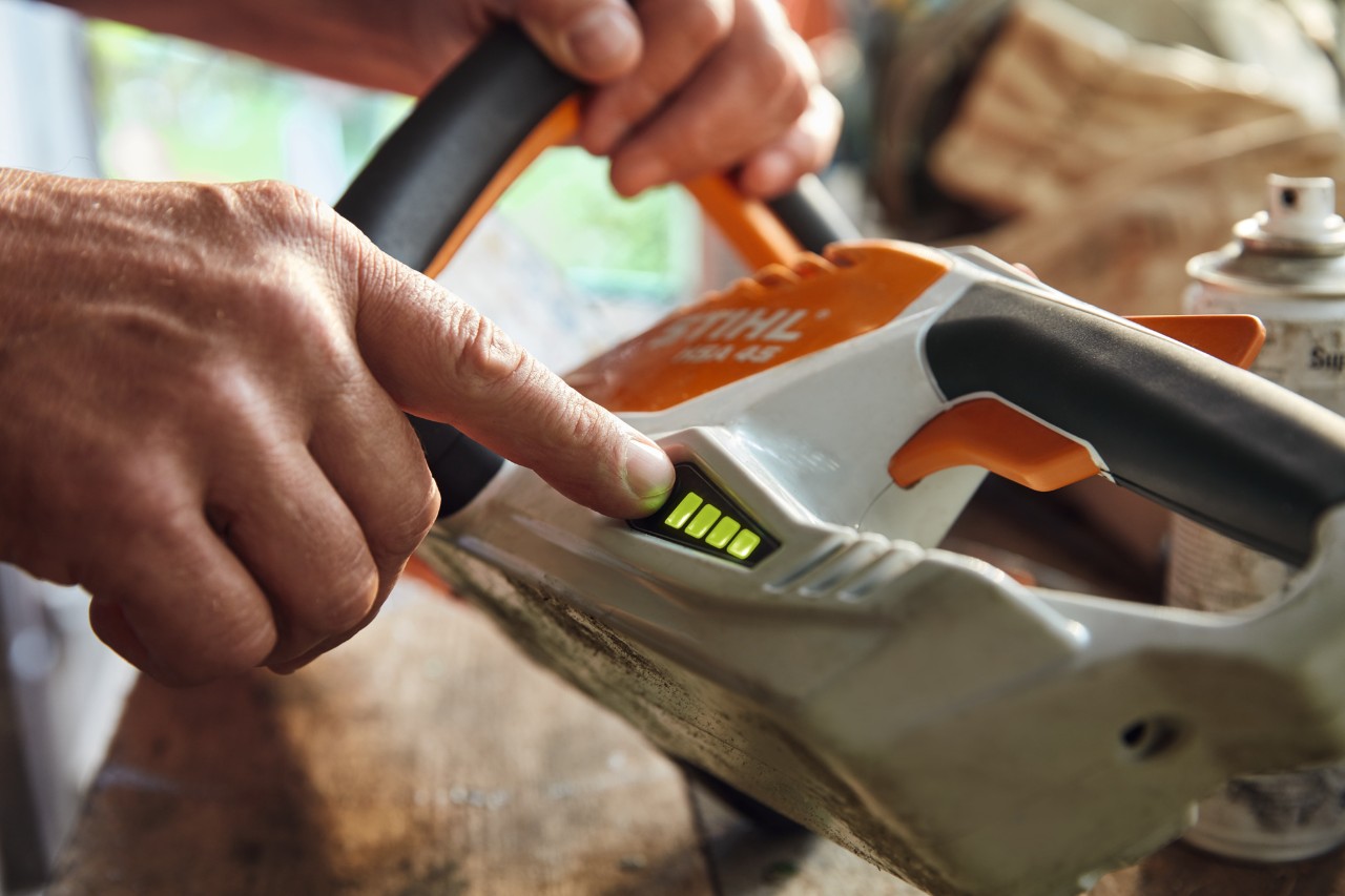 Osoba proverava nivo napunjenosti bežičnih trimera za živu ogradu STIHL HSA 45.