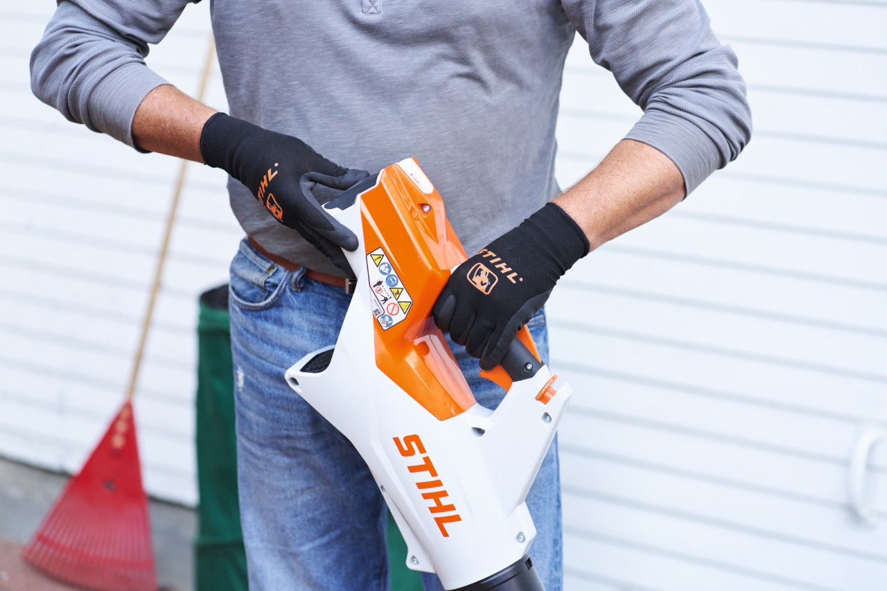 Osoba u sivom džemperu i farmerkama sa STIHL duvačem u ruci