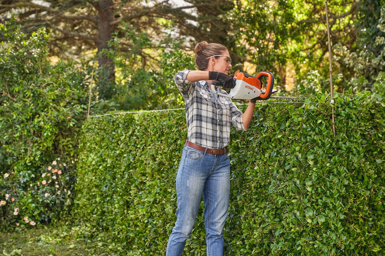 Žena oblikuje živu ogradu pomoću STIHL baterijskih makaza za živu ogradu HSA 45