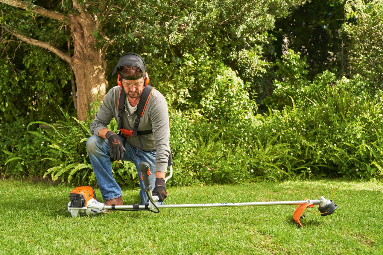 Čovek postavlja benzinsku motornu kosu STIHL FS 91 na tlo kako bi je pokrenuo
