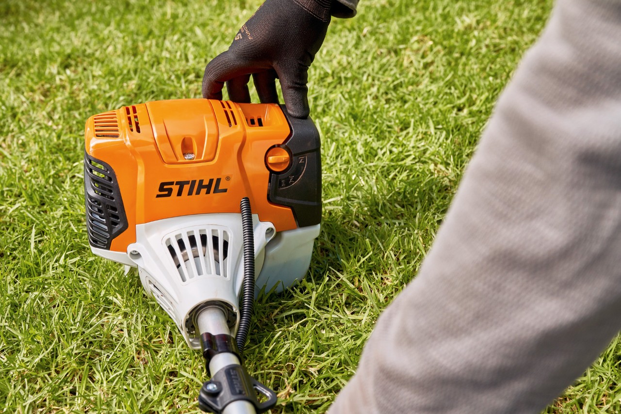 Čovek čvrsto pritiska benzinsku motornu kosu STIHL FS 91 na tlo