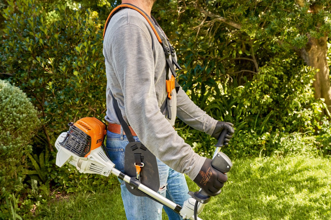 Čovek podiže benzinsku motornu kosu STIHL FS 91 sa tla kako bi započeo košenje 