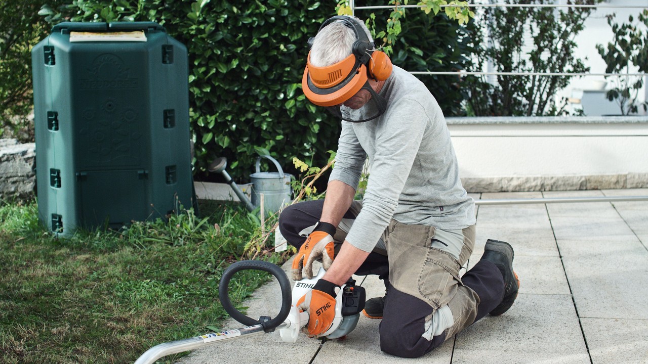 Osoba u zaštitnoj odeći pritiska benzinsku motornu kosu STIHL FS 38 na tlo