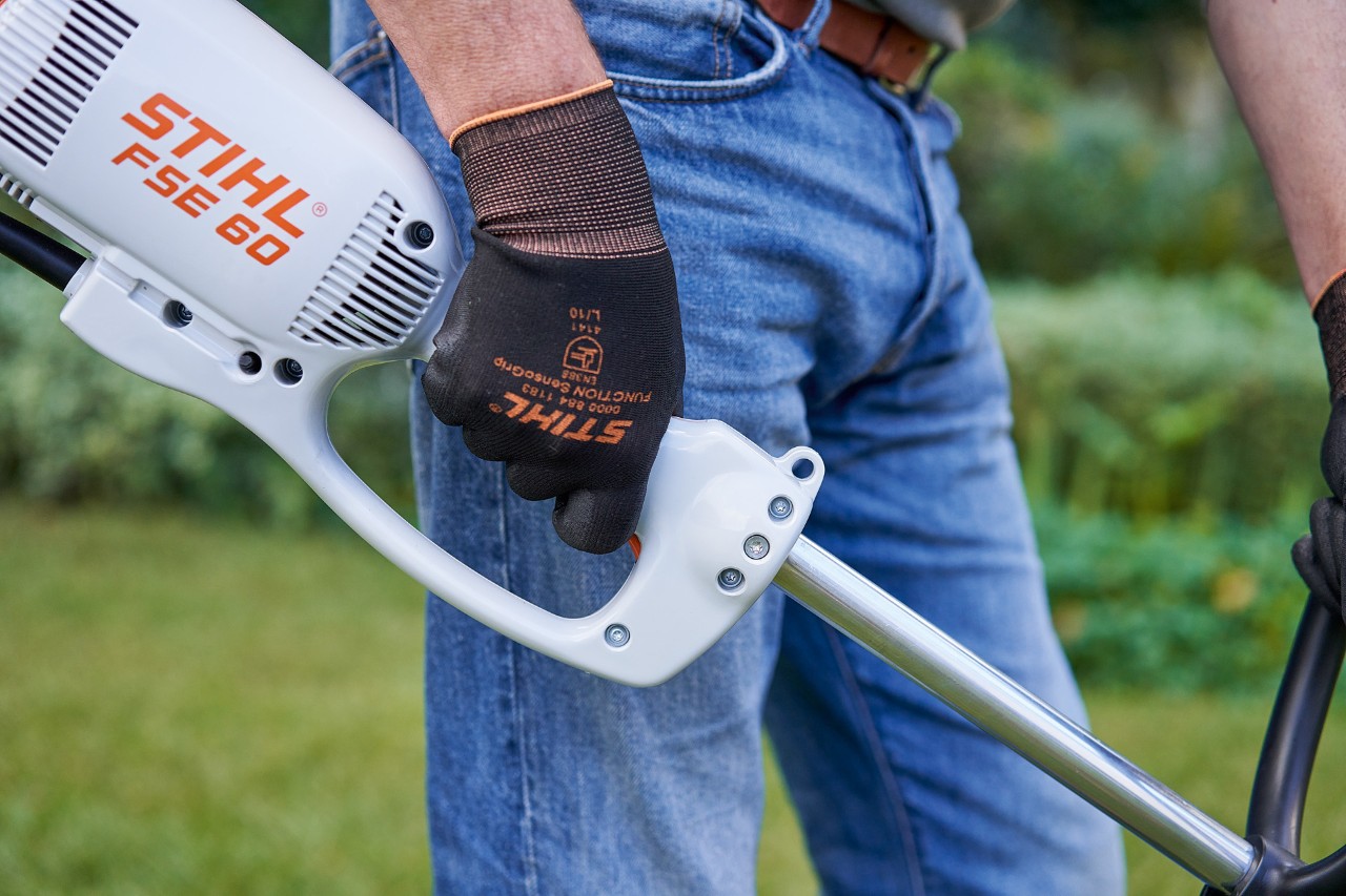 Čovek pritiska prekidač na komandnoj ručki električne motorne kose STIHL FSE 60