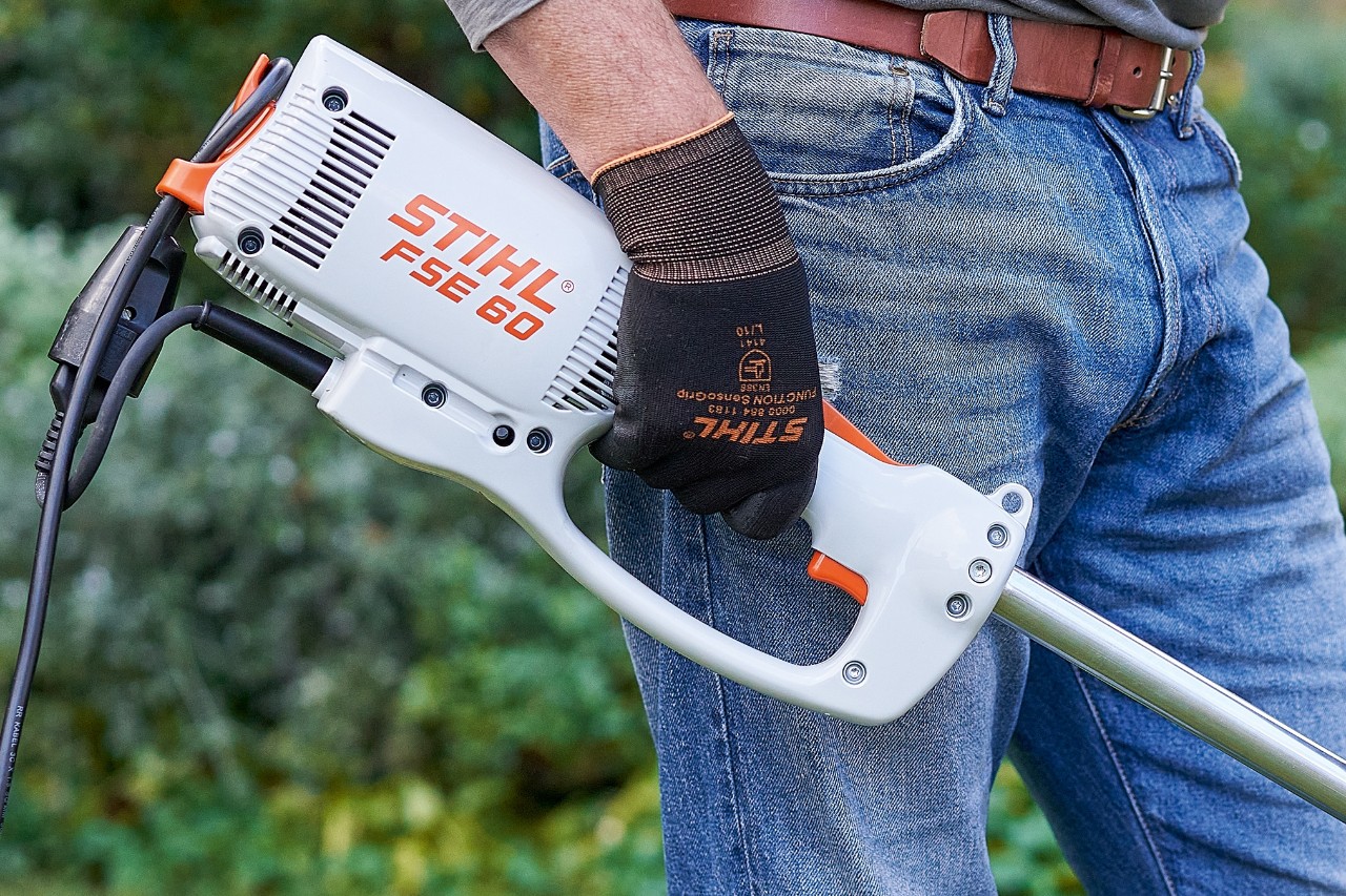 Čovek aktivira prekidač kako bi isključio električnu motornu kosu STIHL FSE 60.