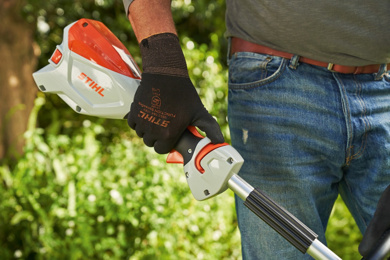 Čovek sa zaštitnim rukavicama gura klizač za odblokiranje akumulatorske motorne kose STIHL FSA 60 do obuhvatne ručke