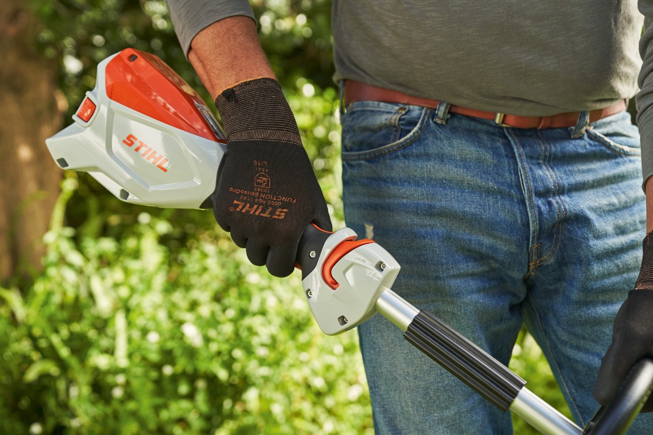Čovek sa zaštitnim rukavicama aktivira ručicu menjača akumulatorske motorne kose STIHL FSA 60 kako bi je pokrenuo