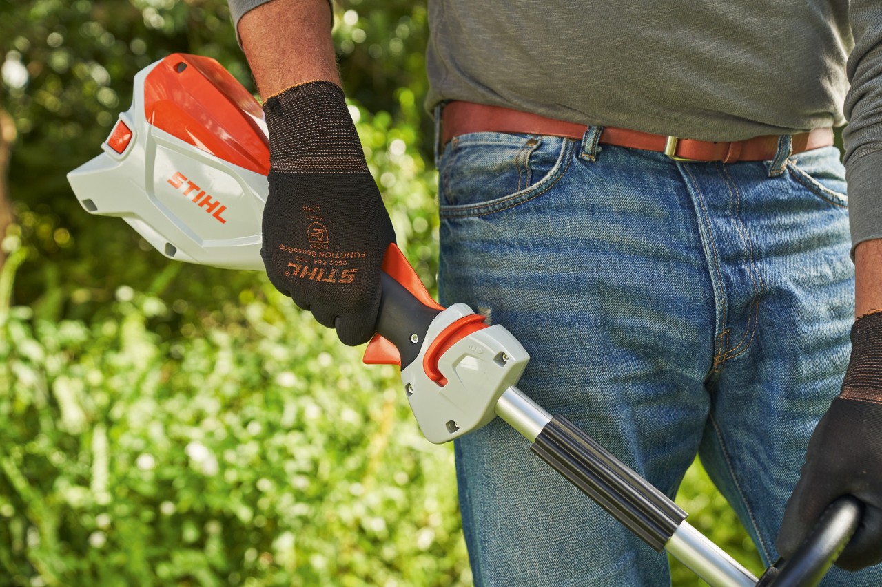 Čovek sa zaštitnim rukavicama pušta ručicu menjača akumulatorske motorne kose STIHL FSA 60 kako bi je isključio