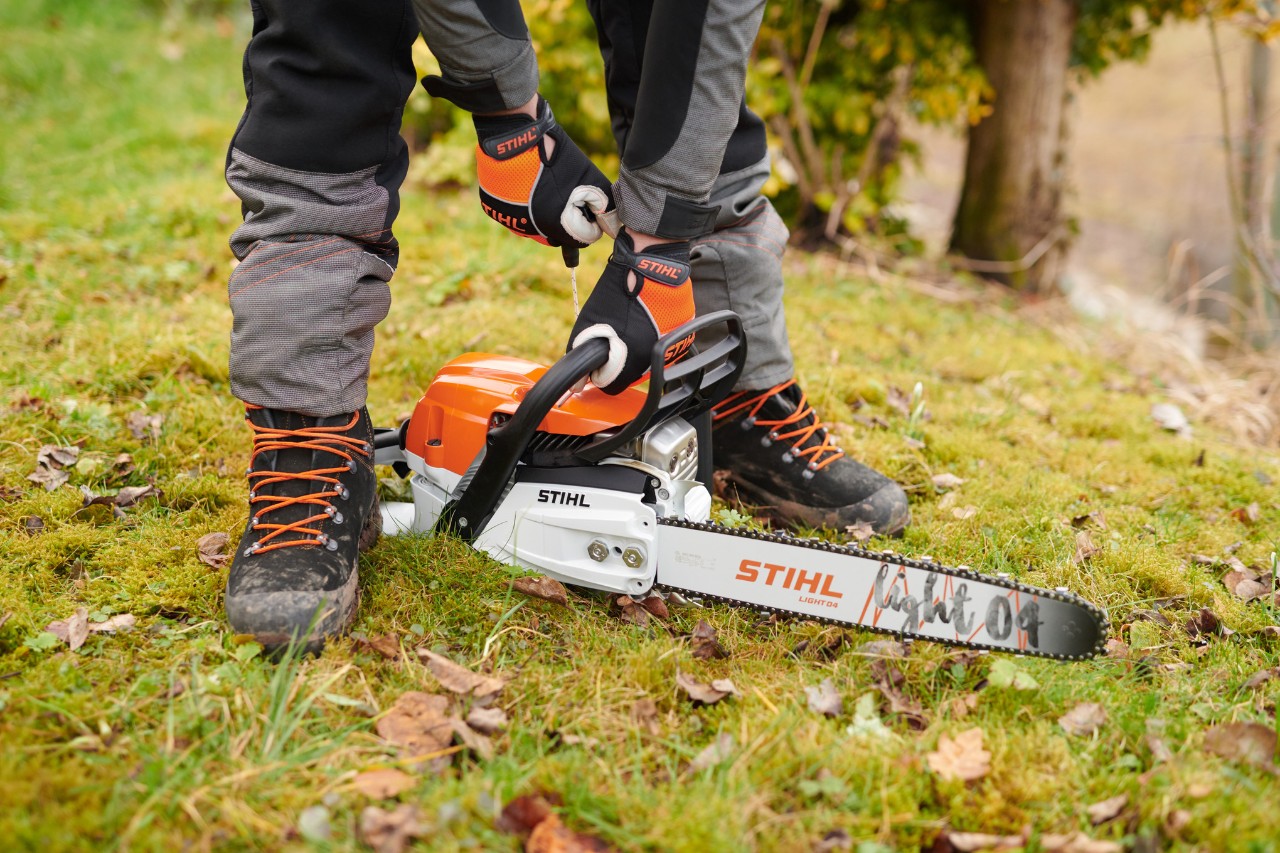 Lančana testera STIHL MS261CM postavljena je na zemlju kako bi osoba mogla bezbedno da je pokrene.
