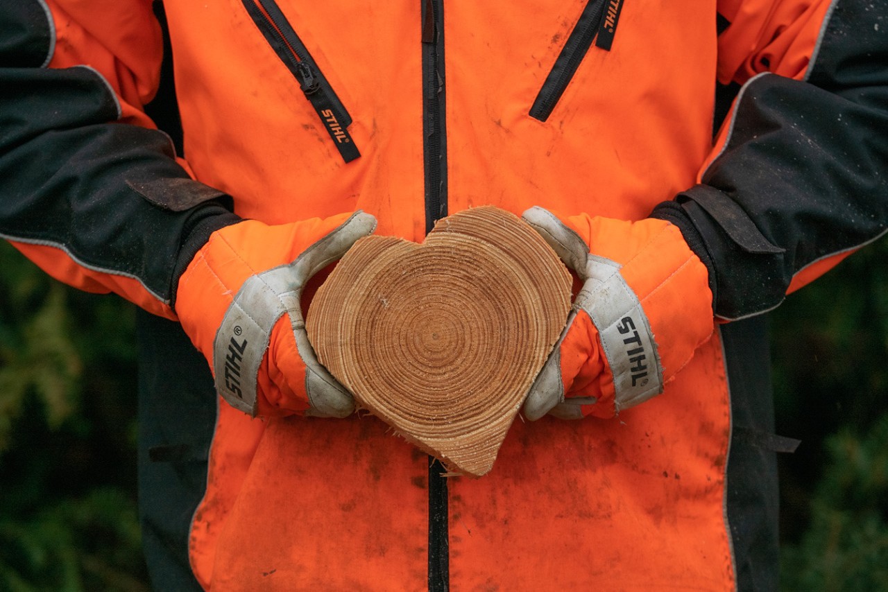 Osoba u STIHL zaštitnoj odeći drži komad drveta u obliku srca u rukama