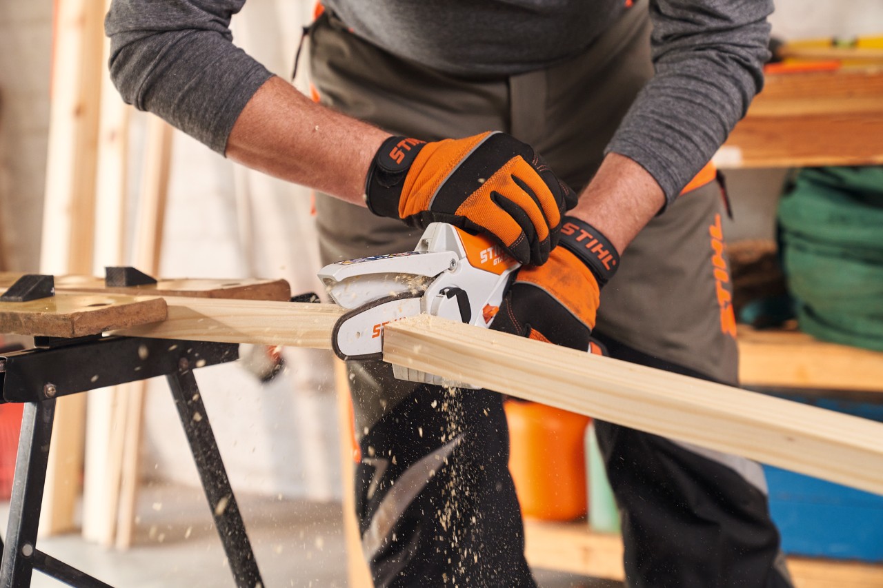 Osoba sa zaštitnim rukavicama STIHL Function Protect skraćuje letve okvira zaklona sekačem STIHL GTA 26