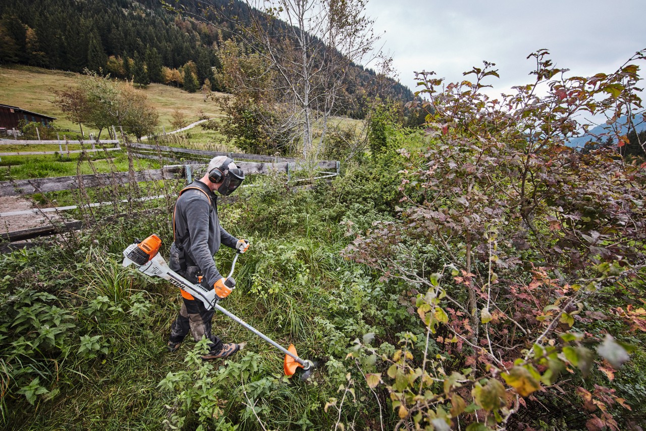 Muškarac u zaštitnoj opremi kosi gusto rastinje koristeći STIHL benzinski trimer FS 311