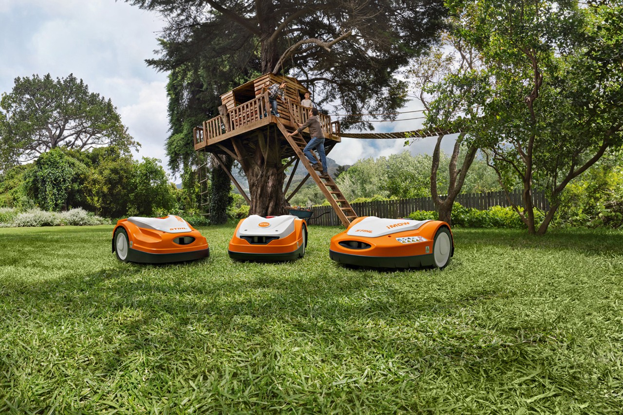 Različite STIHL iMOW® robotske kosačice na zelenoj travi u dvorištu